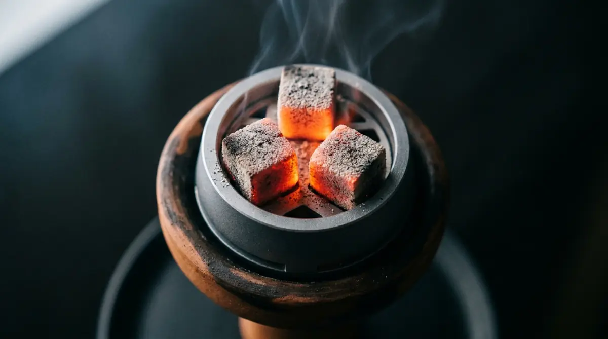 Three glowing hookah charcoal cubes on a heat management device